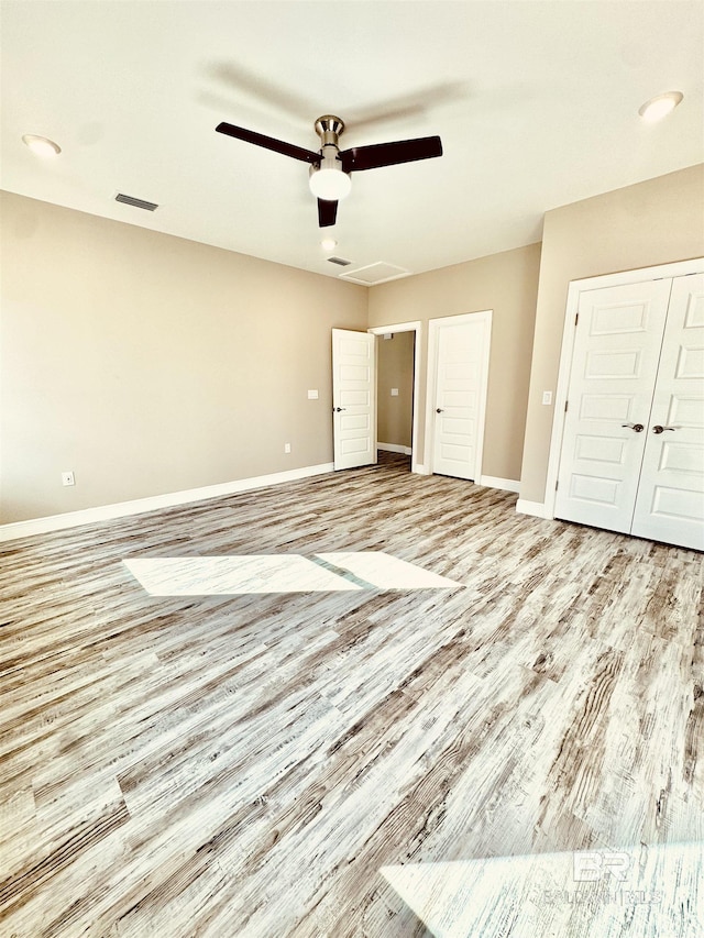 unfurnished bedroom featuring ceiling fan, light hardwood / wood-style floors, and a closet