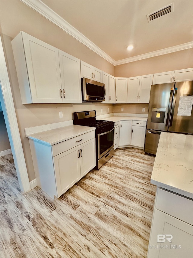 kitchen with white cabinetry, appliances with stainless steel finishes, crown molding, and light hardwood / wood-style floors