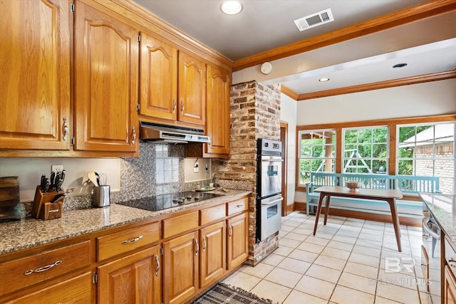 kitchen with light tile patterned floors, stainless steel double oven, ornamental molding, black electric cooktop, and light stone counters