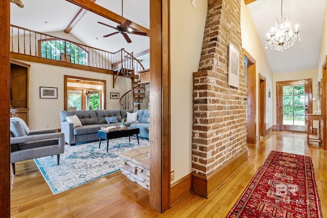 living room featuring light wood-type flooring, ceiling fan with notable chandelier, a healthy amount of sunlight, and high vaulted ceiling