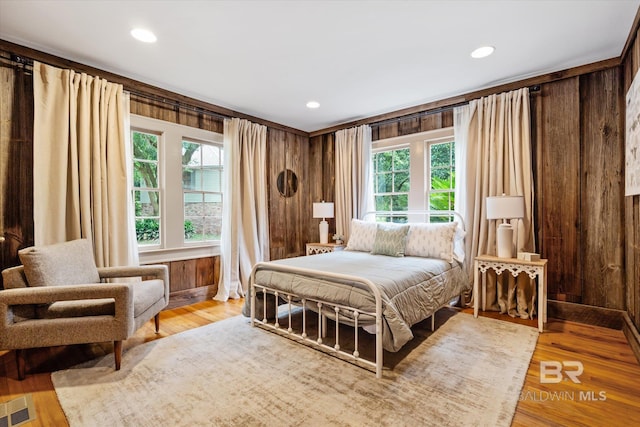 bedroom featuring crown molding, wood walls, and light wood-type flooring