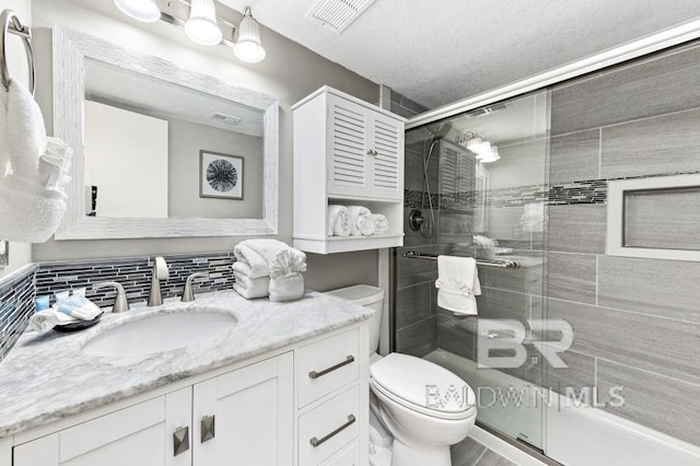 bathroom with vanity, a shower with door, toilet, a textured ceiling, and tasteful backsplash