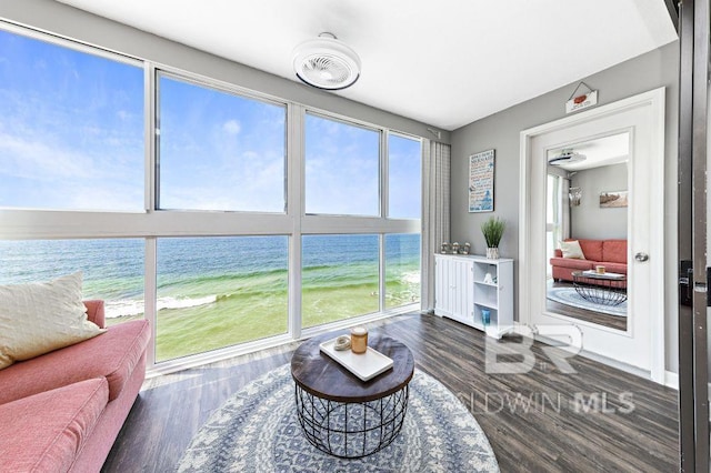 sunroom featuring a view of the beach, a water view, and a wealth of natural light