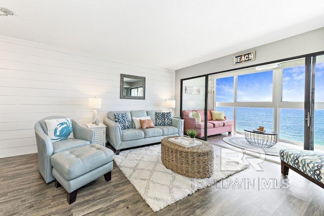 living room with wood walls, a water view, and dark wood-type flooring