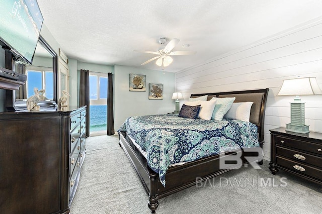 carpeted bedroom featuring access to exterior, a textured ceiling, a water view, and ceiling fan