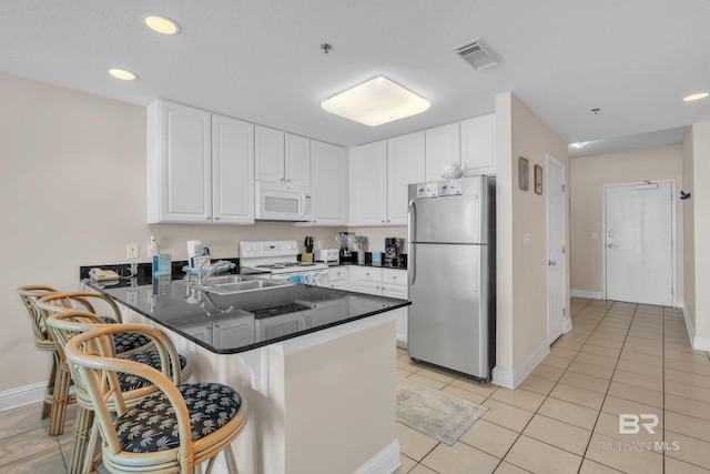 455 E Beach Blvd Unit 511, Gulf Shores, AL 36542 - kitchen featuring white appliances, a breakfast bar area, white cabinets, visible vents, and a peninsula