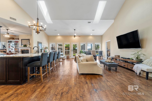 4001 Landfall Dr, Pensacola, FL 32507 - living room with high vaulted ceiling, a skylight, a fireplace, dark wood finished floors, and ceiling fan with notable chandelier