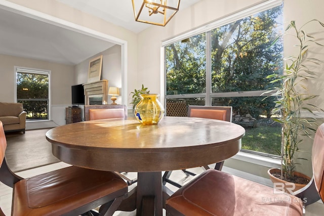 dining area featuring plenty of natural light, lofted ceiling, and an inviting chandelier