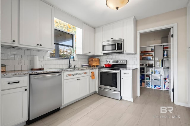 kitchen featuring white cabinets, light stone counters, stainless steel appliances, and tasteful backsplash