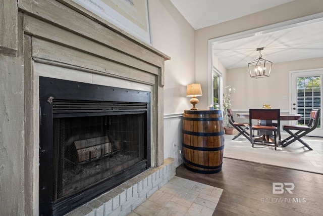 room details featuring a fireplace, hardwood / wood-style flooring, and an inviting chandelier