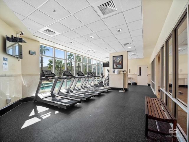 workout area featuring a wall of windows and a drop ceiling