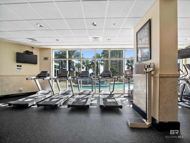 gym featuring floor to ceiling windows and a paneled ceiling