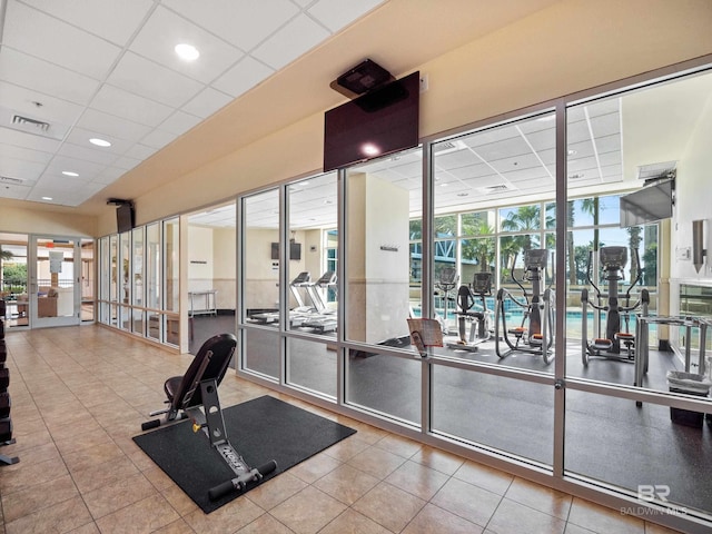 workout area featuring a wall of windows, tile patterned floors, and a paneled ceiling