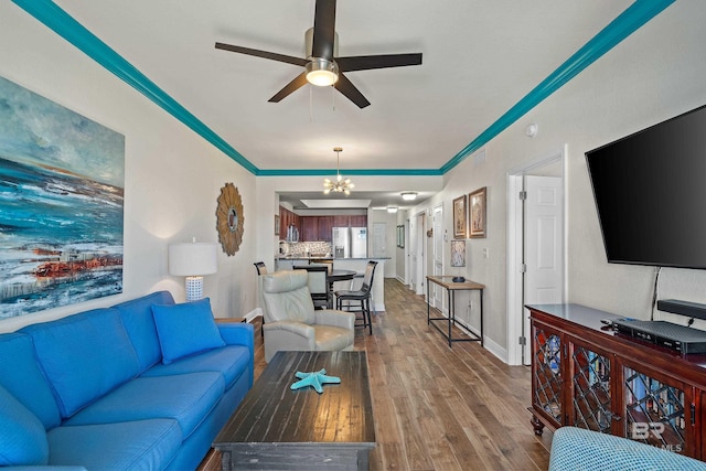 living room with ceiling fan with notable chandelier, hardwood / wood-style flooring, and ornamental molding