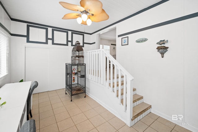 stairway with ceiling fan, tile patterned floors, and ornamental molding