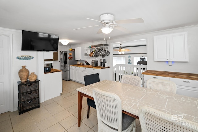 tiled dining area with ceiling fan and ornamental molding