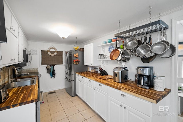 kitchen with white cabinetry, ornamental molding, butcher block countertops, and sink