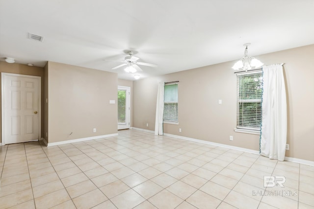 unfurnished room with ceiling fan with notable chandelier, a healthy amount of sunlight, and light tile patterned floors