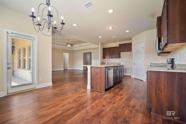 kitchen with light stone counters, pendant lighting, an island with sink, dark wood-type flooring, and stainless steel appliances