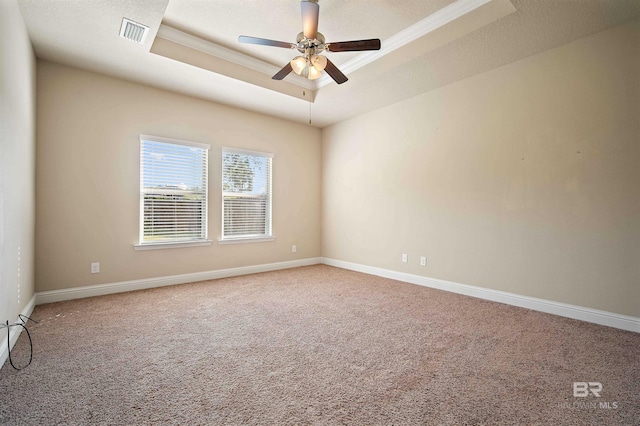 unfurnished room with ceiling fan, a tray ceiling, crown molding, and carpet