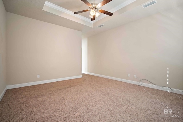 carpeted spare room with ceiling fan, crown molding, and a tray ceiling