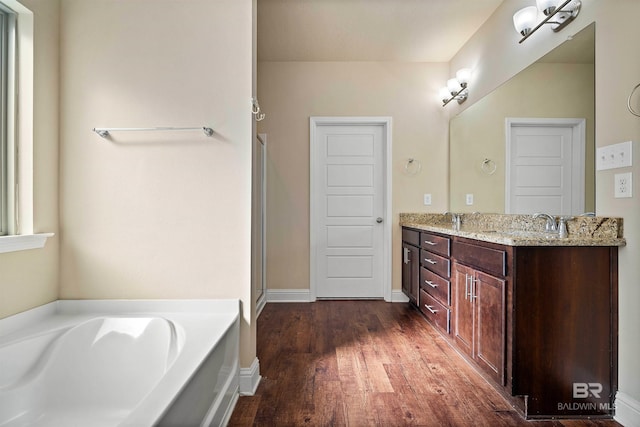 bathroom with wood-type flooring, vanity, and a bathing tub