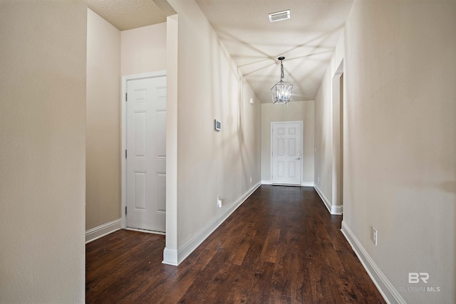 hallway with a textured ceiling, a chandelier, and dark hardwood / wood-style flooring