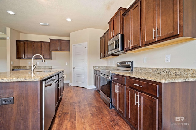 kitchen featuring light stone counters, dark hardwood / wood-style floors, stainless steel appliances, sink, and a textured ceiling