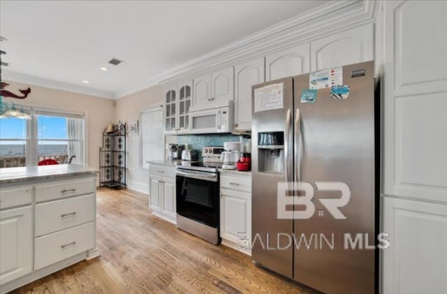 2223 W Beach Blvd, Gulf Shores, AL 36542 - kitchen with crown molding, light countertops, light wood finished floors, appliances with stainless steel finishes, and white cabinets
