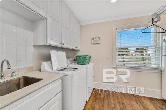 2223 W Beach Blvd, Gulf Shores, AL 36542 - laundry room featuring crown molding, separate washer and dryer, a sink, cabinet space, and wood finished floors