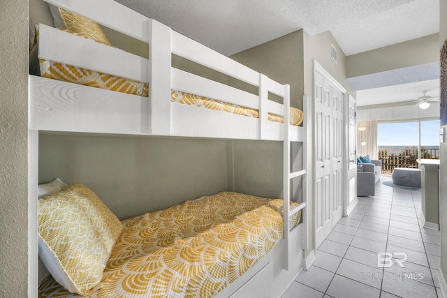 tiled bedroom with a textured ceiling and a closet