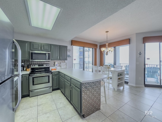 kitchen with stainless steel appliances, a notable chandelier, kitchen peninsula, pendant lighting, and decorative backsplash