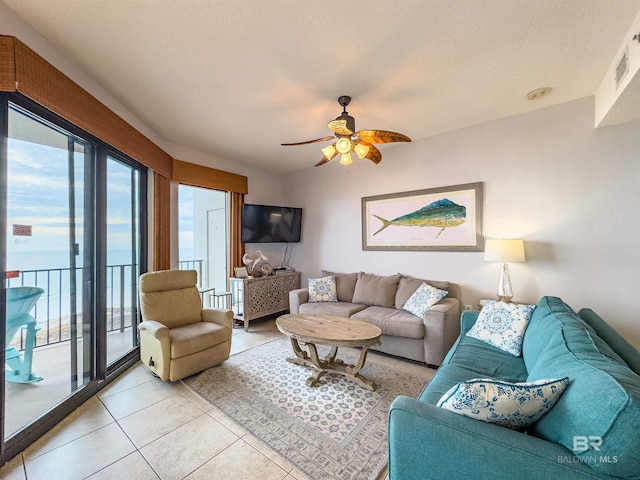 living room featuring a textured ceiling, a water view, ceiling fan, and light tile patterned flooring