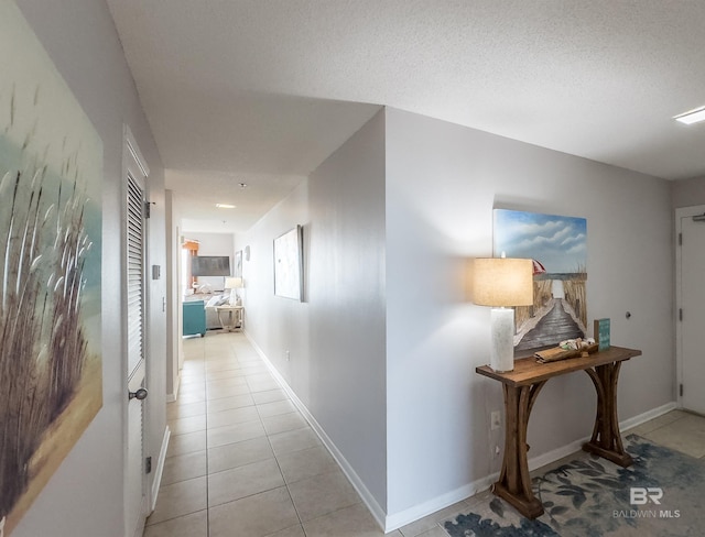 hall with light tile patterned floors and a textured ceiling