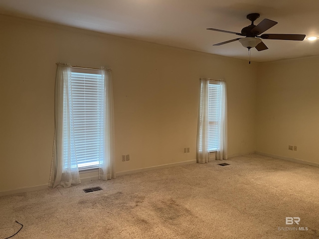 carpeted spare room featuring healthy amount of natural light, ceiling fan, and baseboards