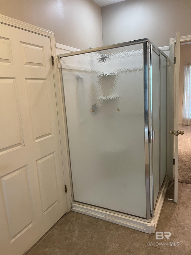 full bathroom with tile patterned flooring and a shower stall