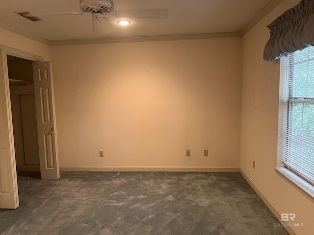 unfurnished bedroom featuring dark colored carpet, crown molding, baseboards, and ceiling fan