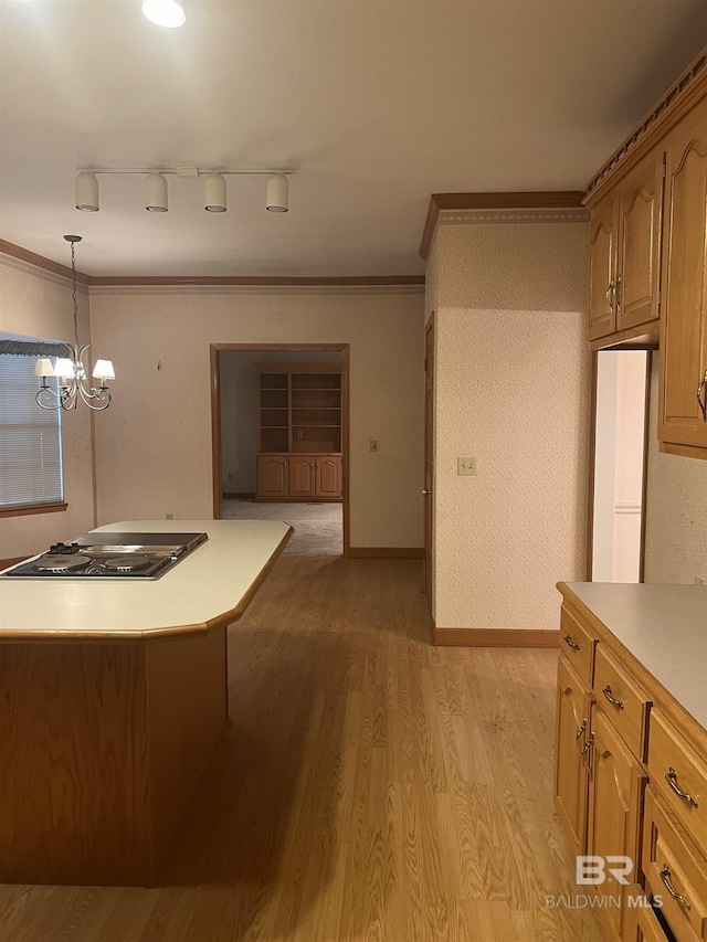 kitchen with black electric cooktop, rail lighting, light wood-style flooring, light countertops, and hanging light fixtures