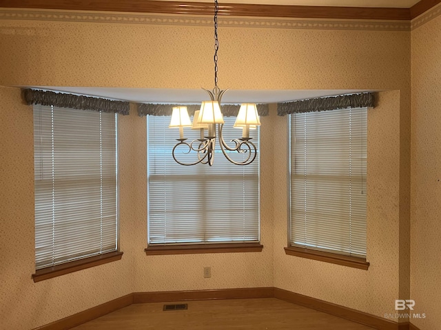 unfurnished dining area featuring a chandelier, wood finished floors, and baseboards