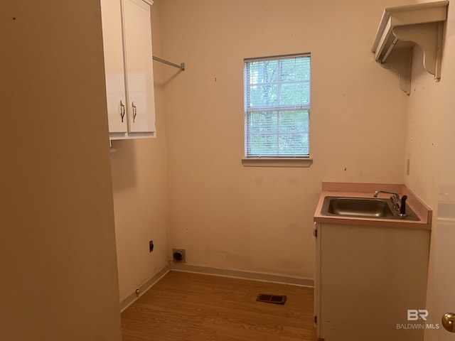 washroom with hookup for an electric dryer, wood finished floors, cabinet space, and baseboards