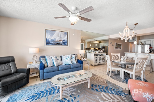 living room featuring a textured ceiling, ceiling fan with notable chandelier, and light tile patterned flooring