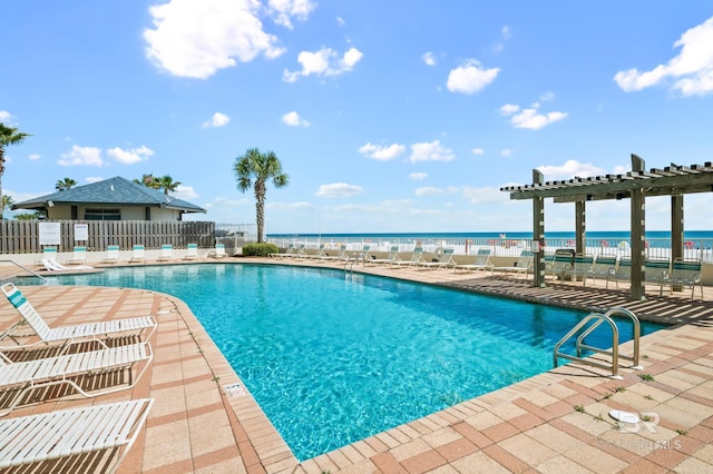 community pool featuring a pergola, a water view, a patio, and fence