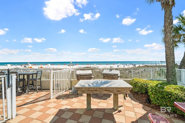 view of patio / terrace with area for grilling, a water view, and a view of the beach