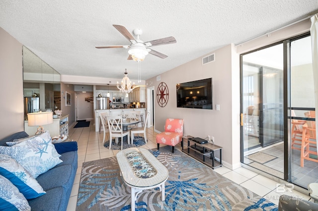 living area with ceiling fan with notable chandelier, visible vents, a textured ceiling, and light tile patterned floors