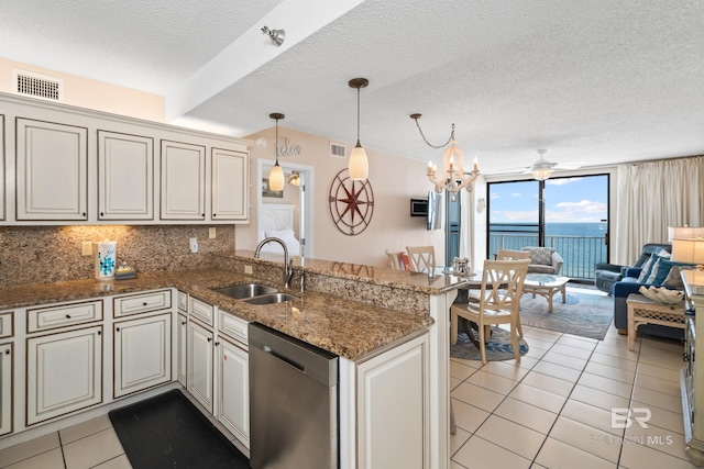 kitchen featuring a peninsula, a sink, open floor plan, stainless steel dishwasher, and decorative backsplash