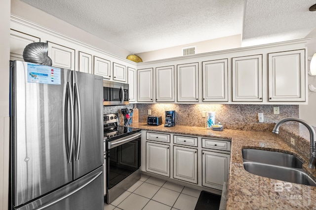 kitchen featuring light tile patterned floors, a sink, visible vents, appliances with stainless steel finishes, and decorative backsplash