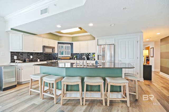 kitchen featuring a center island with sink, white cabinets, and stainless steel refrigerator with ice dispenser