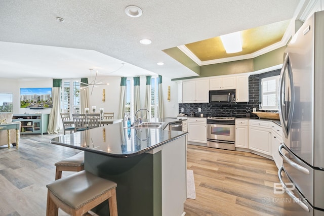 kitchen with white cabinetry, an island with sink, sink, appliances with stainless steel finishes, and a kitchen breakfast bar