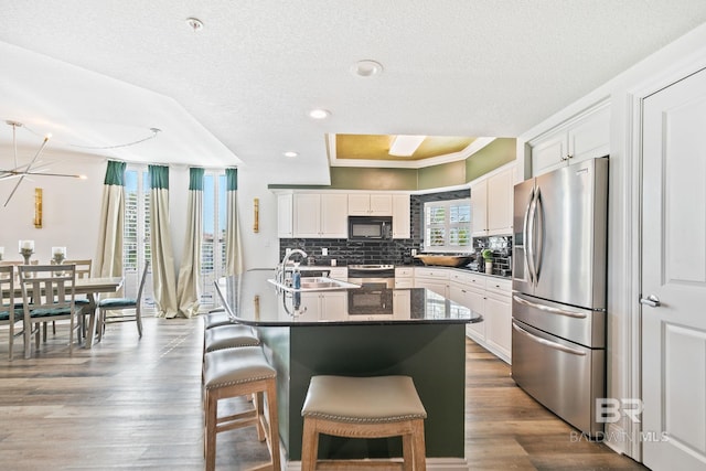 kitchen with white cabinets, sink, and stainless steel fridge