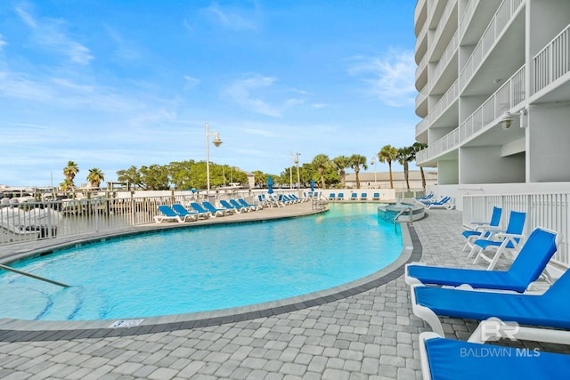 view of swimming pool featuring a patio area and a water view